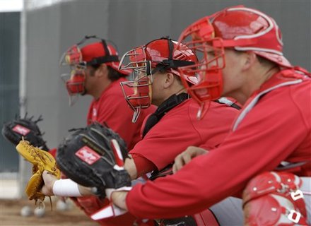 Cincinnati Reds catchers Corky Miller, left, Devin Mesoraco, center, and Chris Denove catch during a bullpen session during baseball spring training Sunday, Feb. 20, 2011, in Goodyear, Ariz. (AP Photo/Mark Duncan)