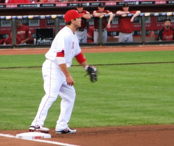 Joey Votto stands with his foot on the bag to field a throw to first base.