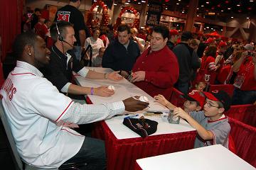 Brandon Phillips signs a baseball for a young fan at Kahn\'s Redsfest XI. Credit: The Cincinnati Reds